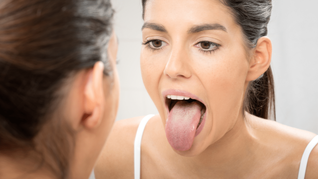 woman sticking out her tongue to examine it